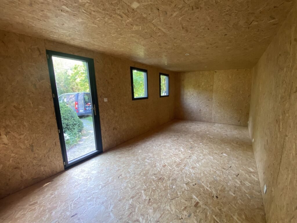 Intérieur du studio fini, parement en panneaux d'OSB et porte vitrée